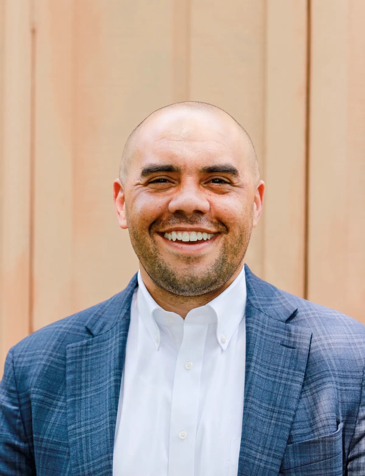 Tyson P. Lee, portrait, in a blue plaid blazer over a white shirt, smiling.